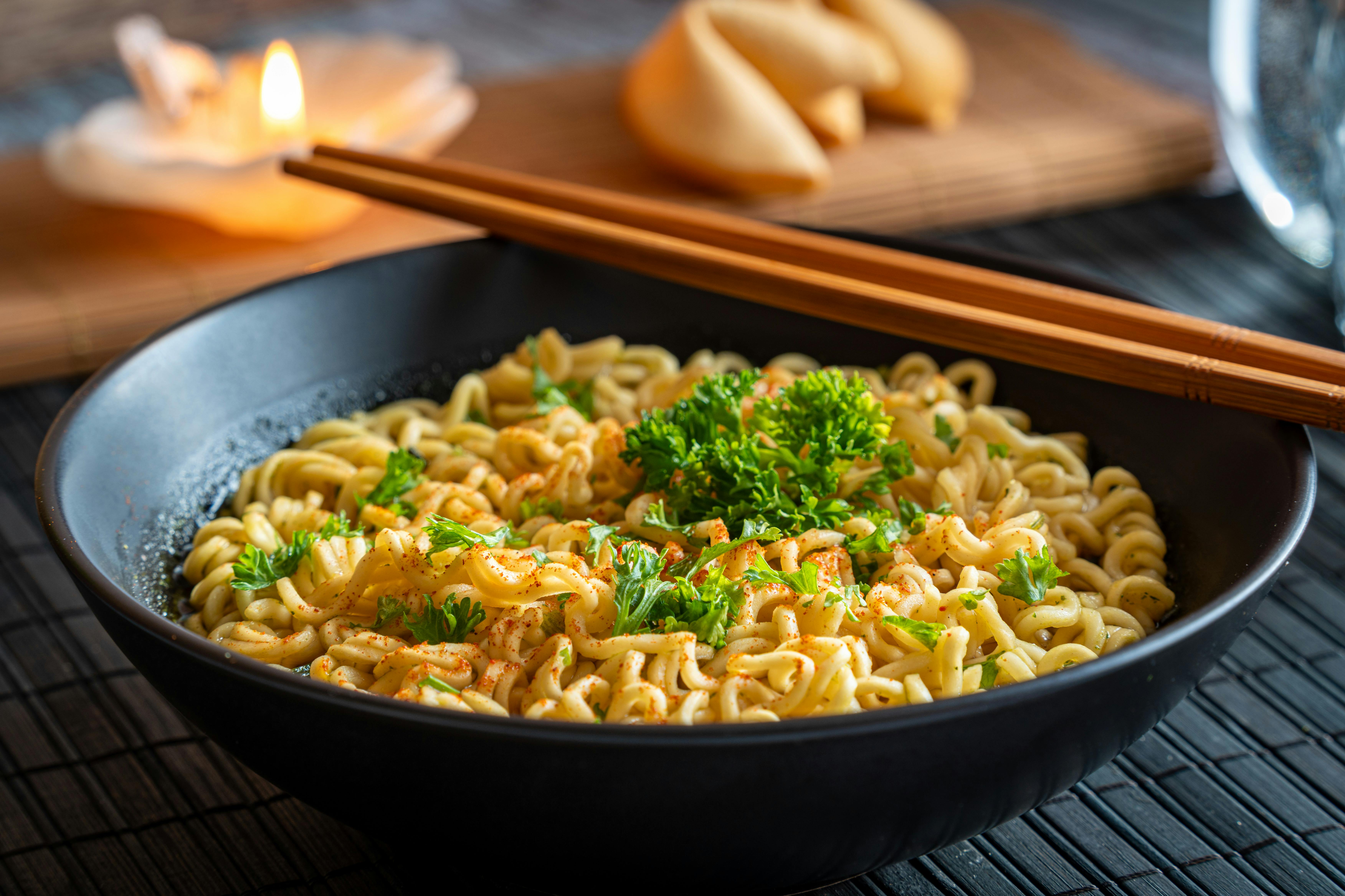 A garlic noodles garnished with parsley and served in a black round dish